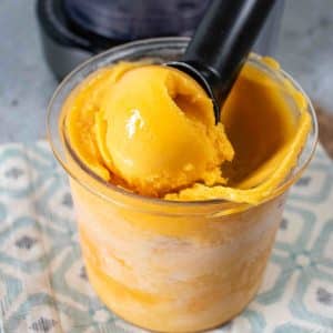 Scooping golden coloured passion fruit puree from the Ninja Creami pot