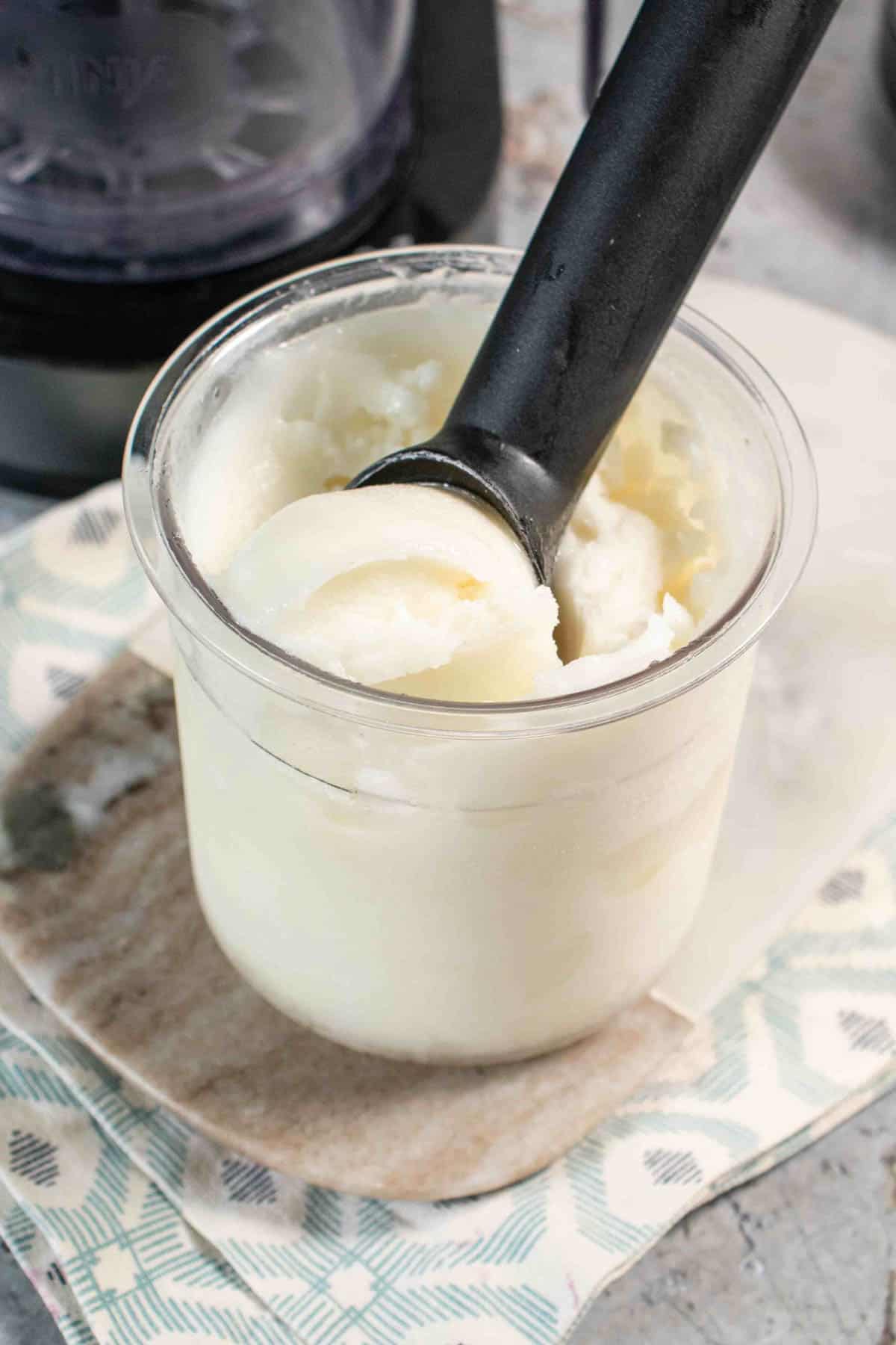 A pot of the palest green Ninja Creami apple sorbet with a scoop being taken out.