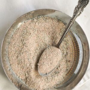 a meal spoon sits in a metal bowl of the pork roast seasoning