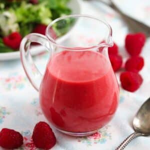 a glass jug of deep red raspberry vinaigrette