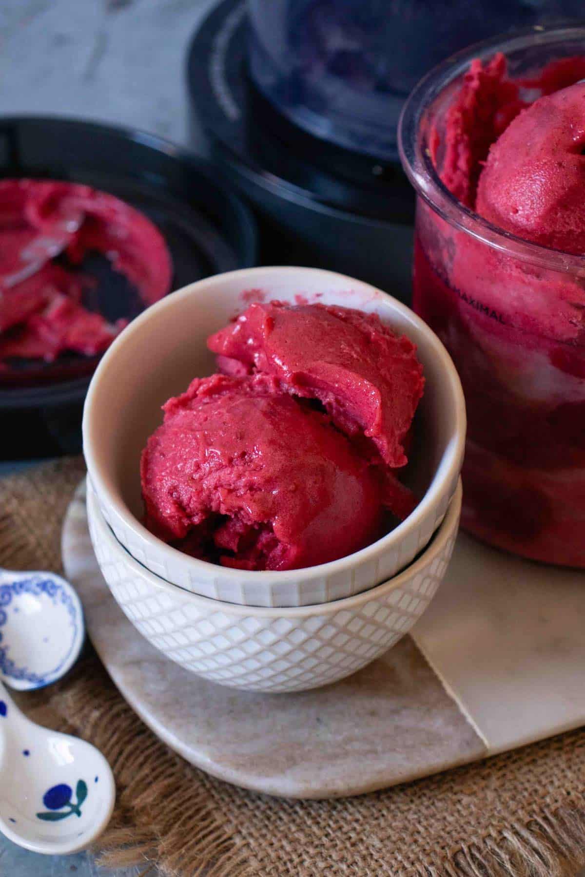 Dark pink blackberry and apple sorbet in a small bowl placed on a marble board