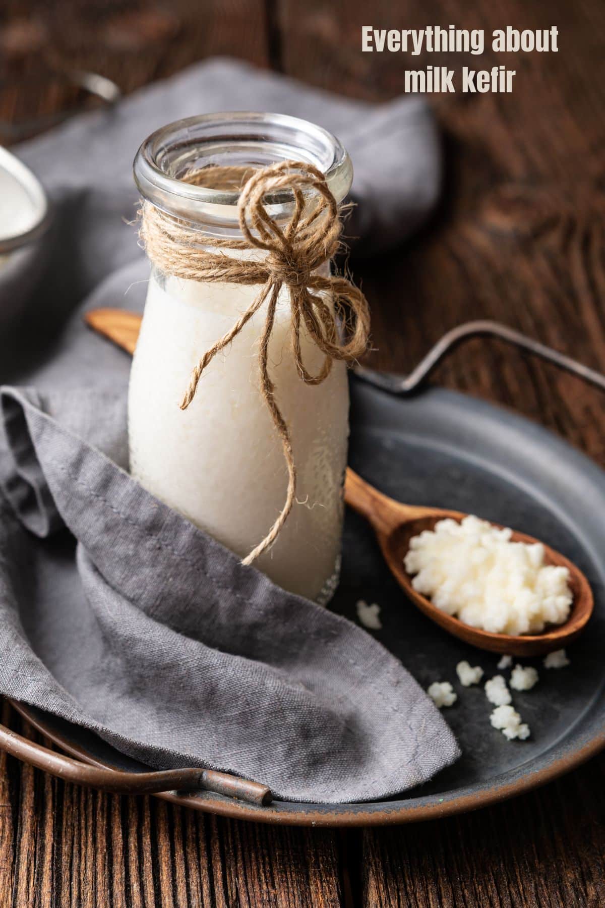 a glass bottle of milk kefir next to a spoon of kefir grains