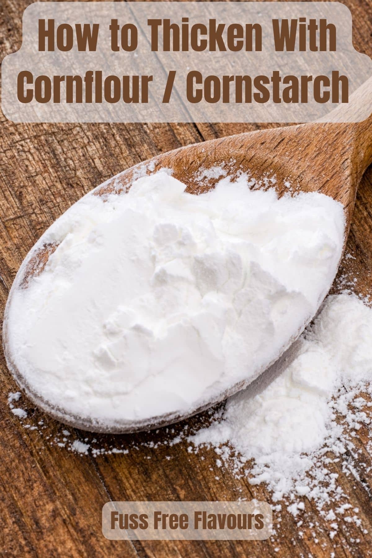 A top down view of a wooden spoon of white cornflour on a wood backdrop