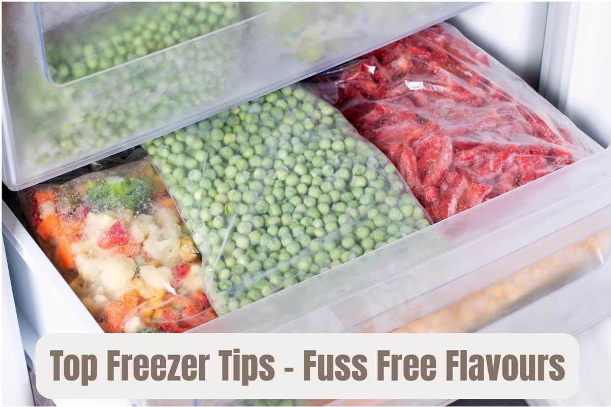 An open freezer drawer, full of bags of frozen vegetables. Peas, mixed veg and sliced bell peppers.