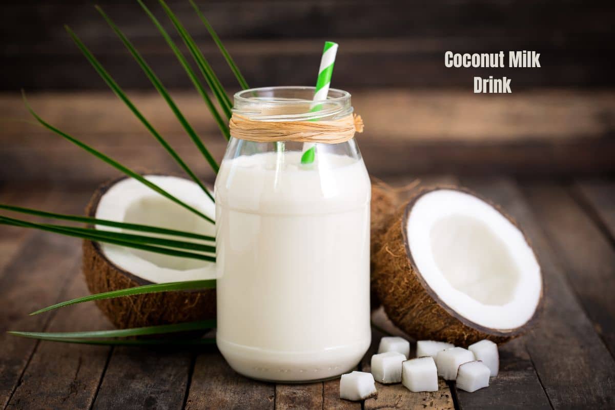 a bottle of creamy white coconut milk with a split coconut behind