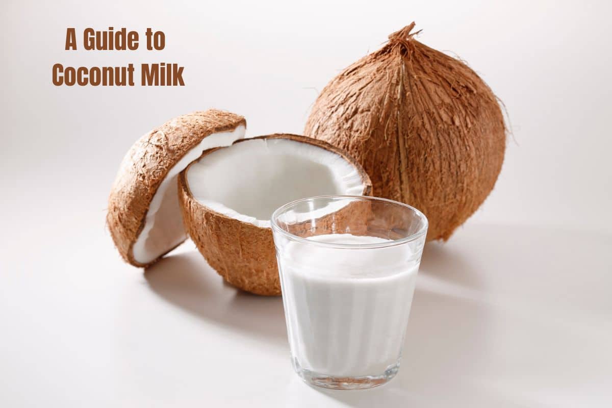 A whole and a split coconut with a glass of creamy white coconut milk in front