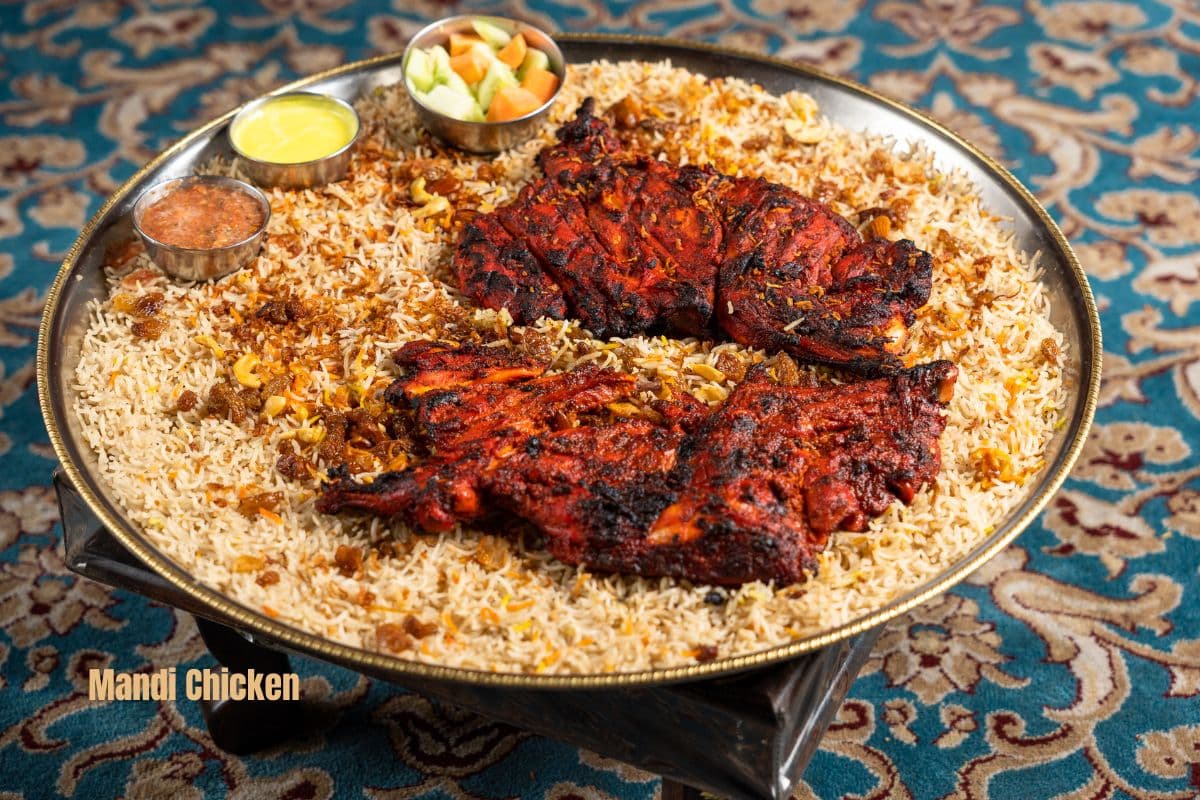 a dish of rice topped with two pieces of mandi chicken