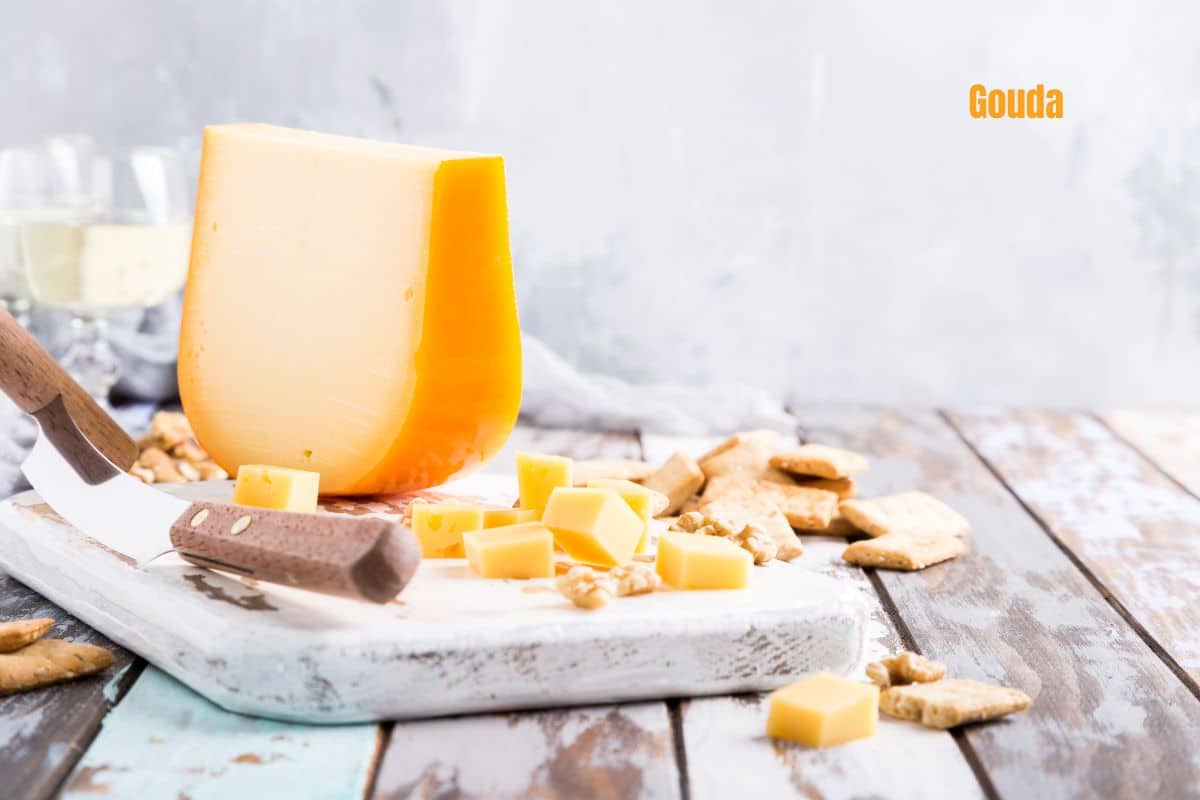 cubes and a wedge of gouda on a white painted board