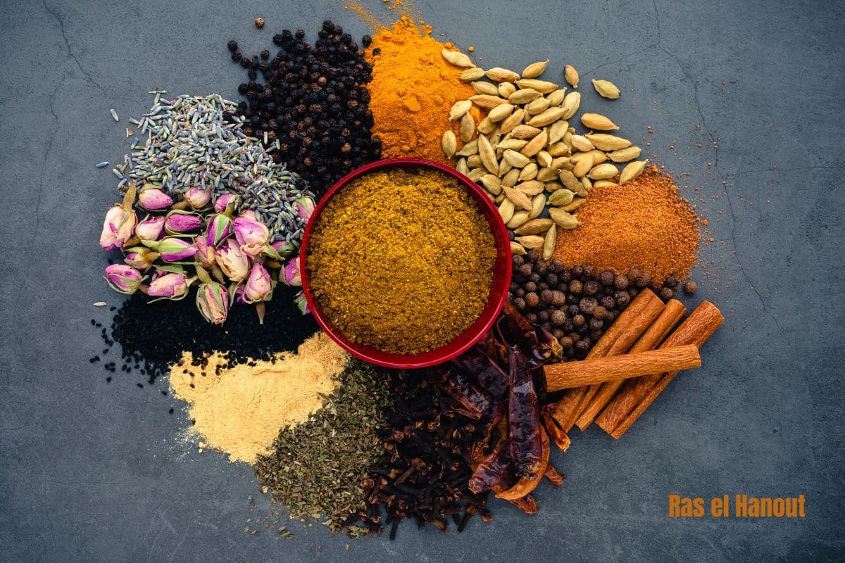 a bowl of ras el hanout surrounded by the spices it contains