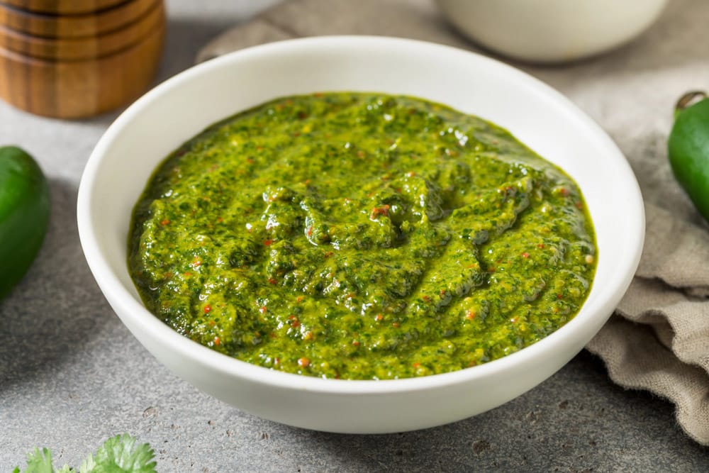 a white bowl of green zhoug sauce