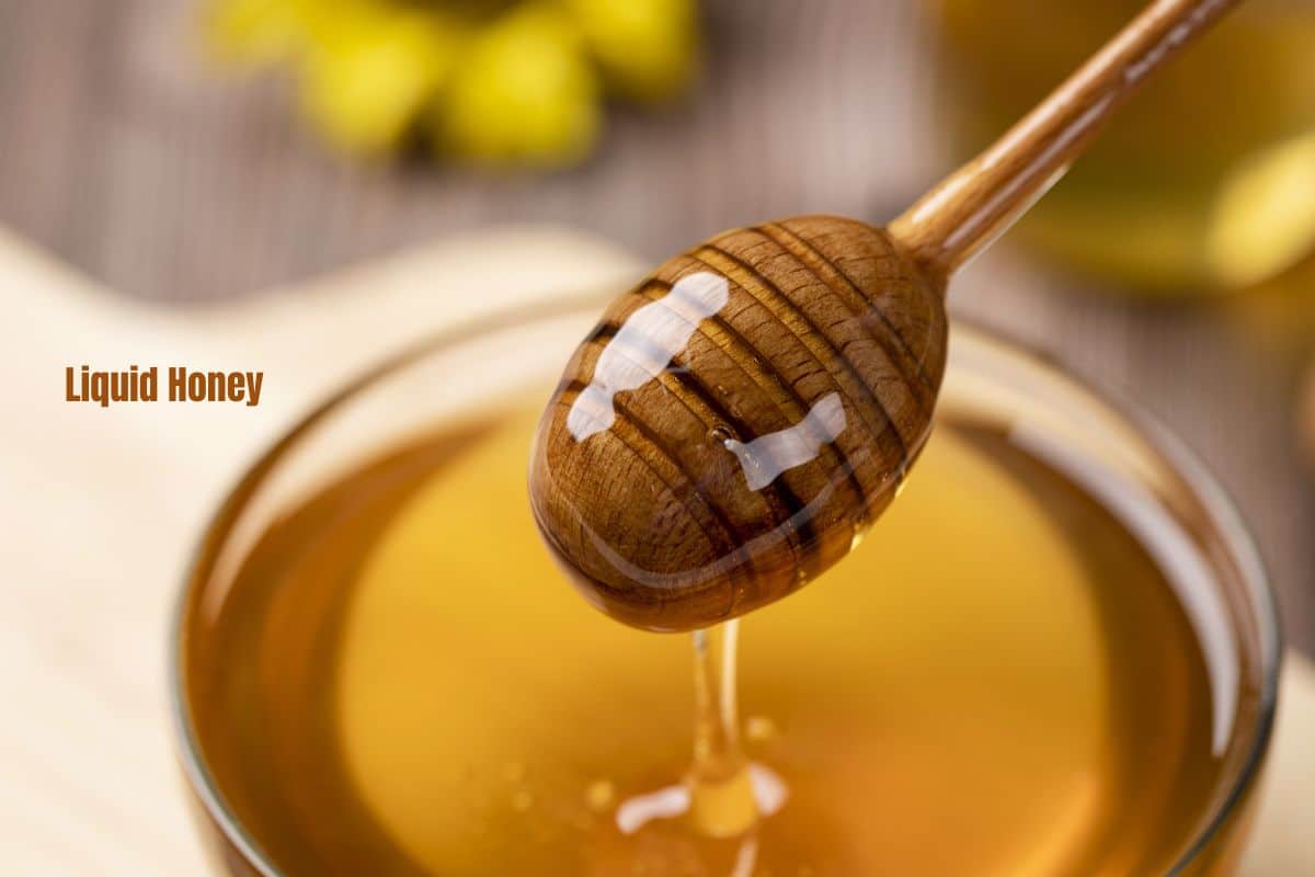a close up of honey drizzling off a honey dipper
