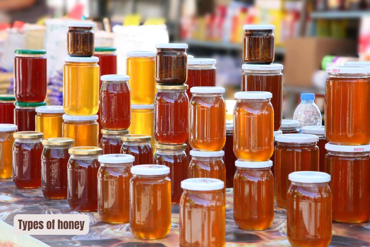 jars of honey of different shades of light brown to pale yellow stacked up at the market