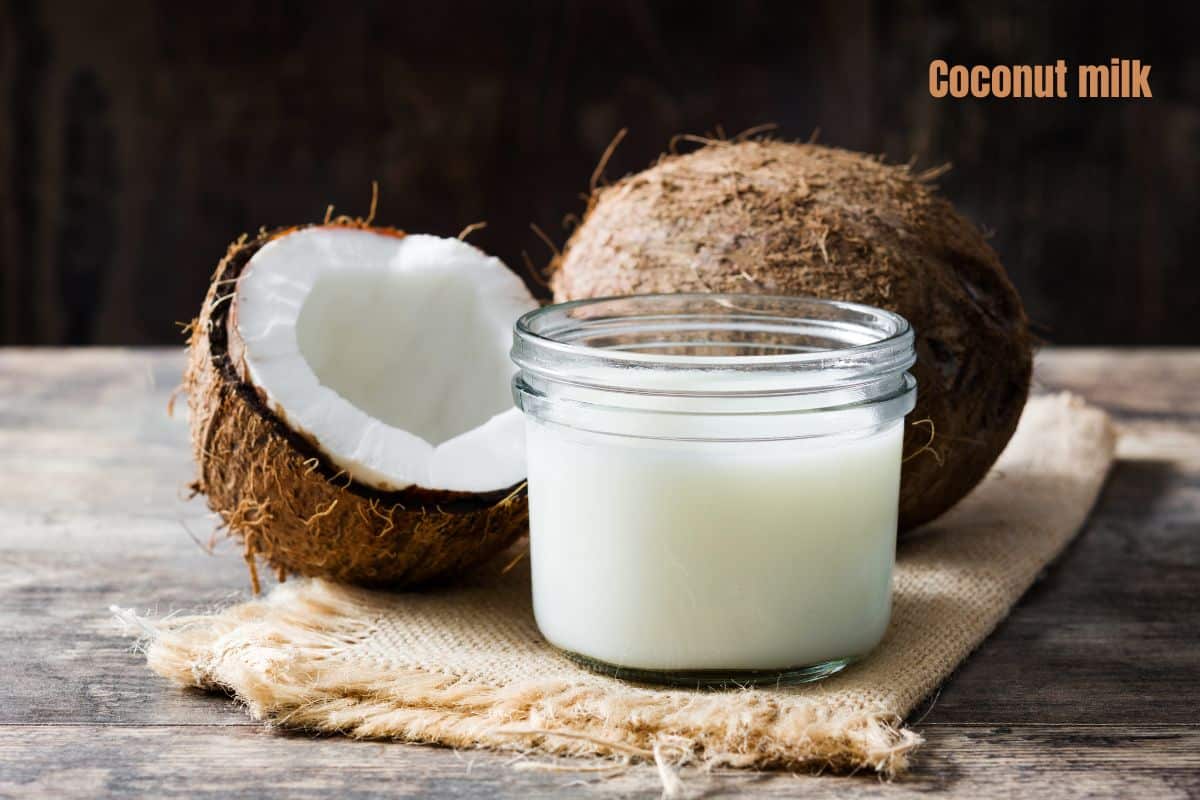 a jar of white coconut milk with a coconut behind