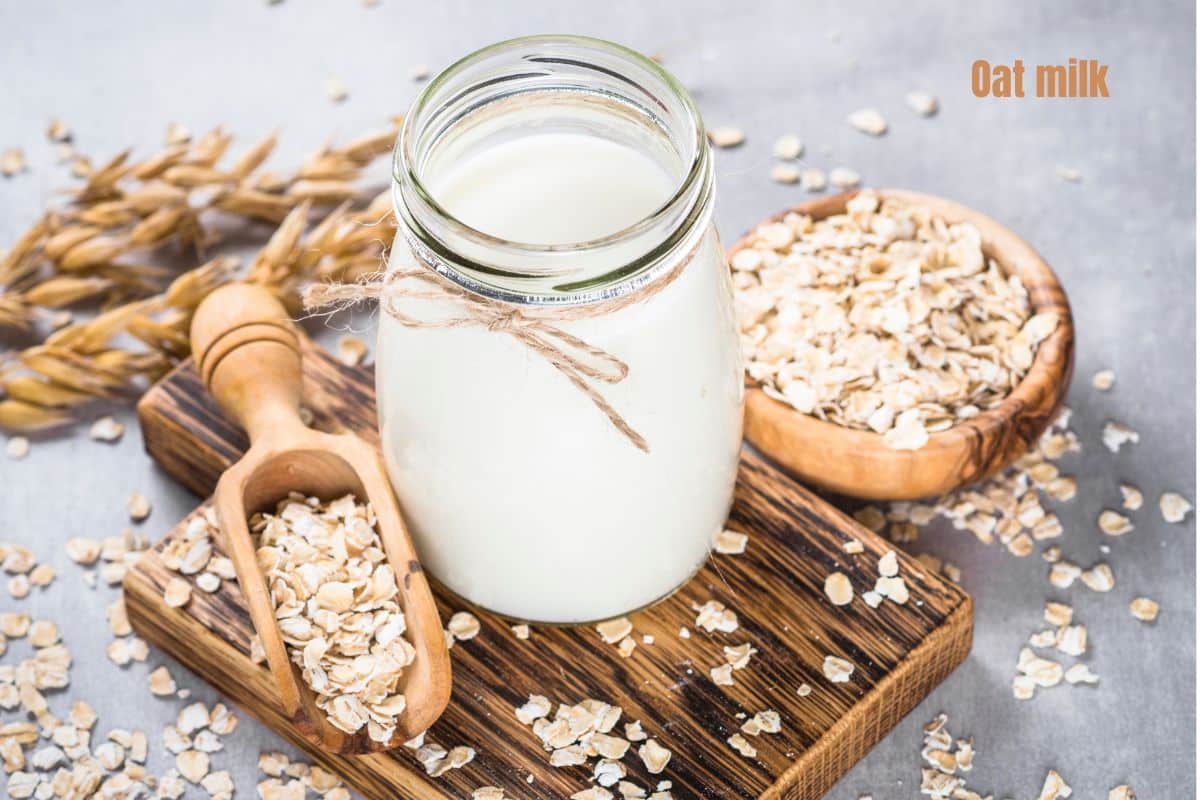 a glass of creamy white oat milk surrounded by rolled oats