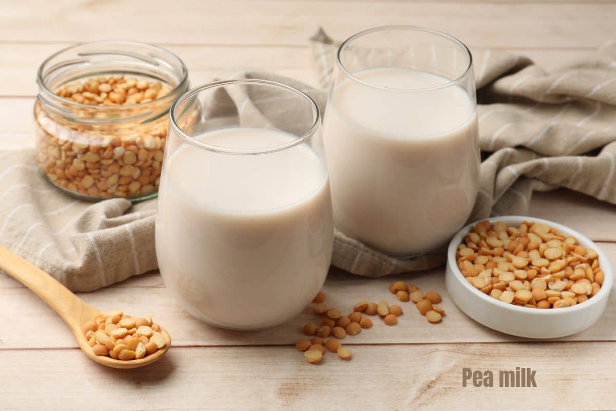 two glasses of creamy pea milk with two bowls of split yellow peas