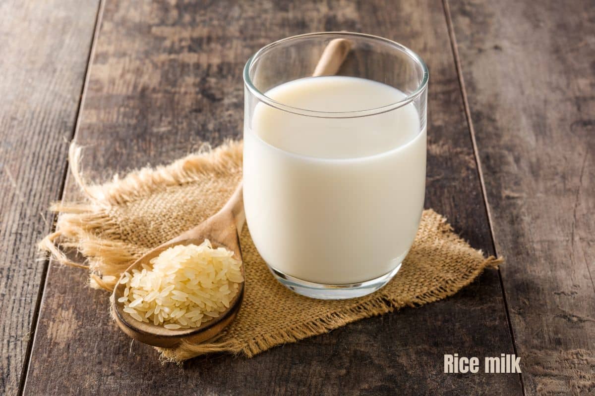 a glass of white rice milk next to a spoon of white rice