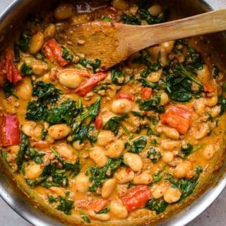a pan of creamy butterbeans in a tomato spinach and nduja sauce